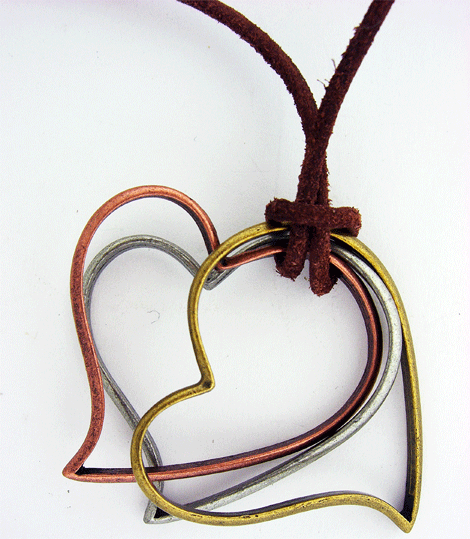 Detailed view of the brown leather necklace featuring a tri-tone gold, copper, and silver heart pendant