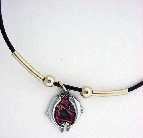 Detailed view of the silver-tone Dolphin Pendant resting on its accompanying black rubber necklace cord